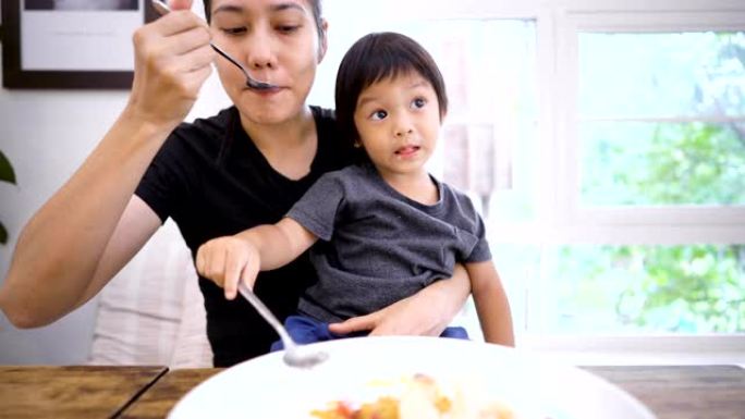 亚洲女性和小男孩在室内一起吃蛋糕和冰糕