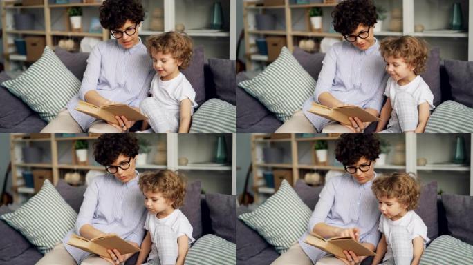 可爱的小孩和他慈爱的母亲一起看书，在公寓里的沙发上微笑