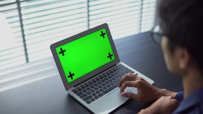 商人看着带有绿屏的笔记本电脑