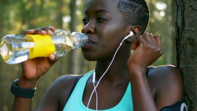 女性慢跑者在森林中喝水4k