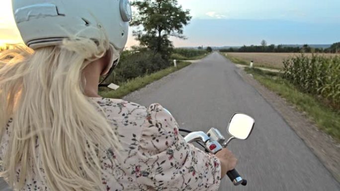 日落时分，SLO MO Mid成年妇女在乡间小路上骑踏板车