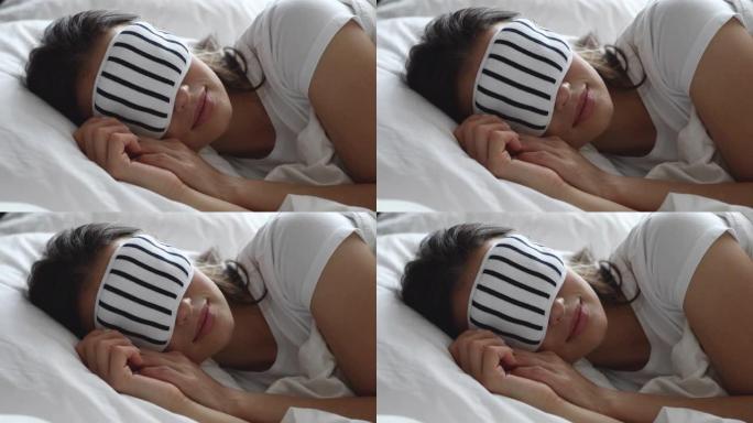 平静健康的年轻女子戴着睡眠面罩躺在床上休息