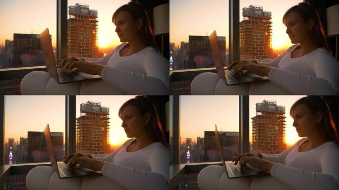 特写: 当金色的阳光照进她的房间时，年轻女子在笔记本电脑上工作