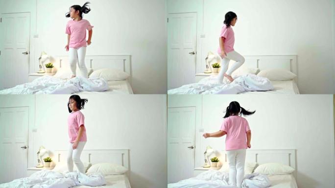 慢动作: 年轻的亚洲快乐女孩在家里的床上跳舞很开心