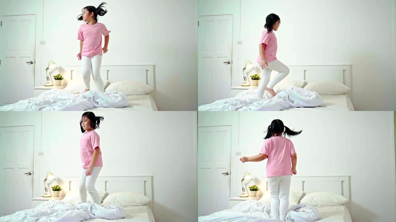 慢动作: 年轻的亚洲快乐女孩在家里的床上跳舞很开心