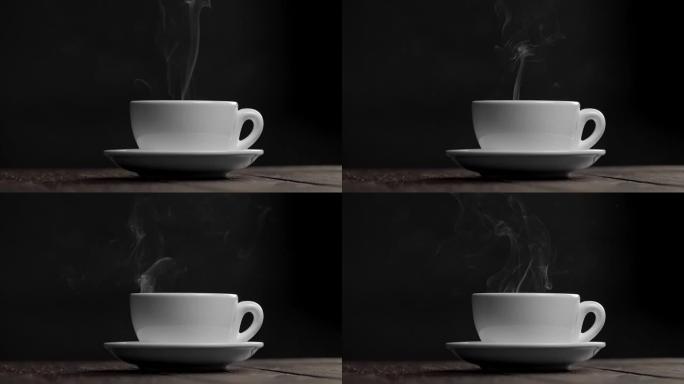 在黑色背景下的碟子上热的白茶或咖啡杯。杯子里冒出蒸汽或烟雾。慢动作镜头