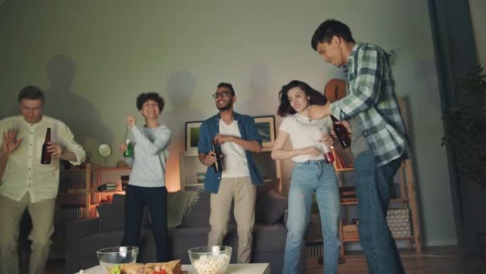 多种族的年轻人在家庭聚会上跳舞叮叮当的瓶子