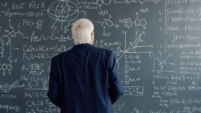 经验丰富的科学家在大学课堂上走到黑板墙看公式