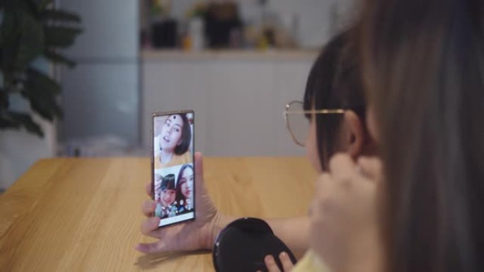 亚洲家庭使用电话，通过在家中的视频通话与朋友聊天