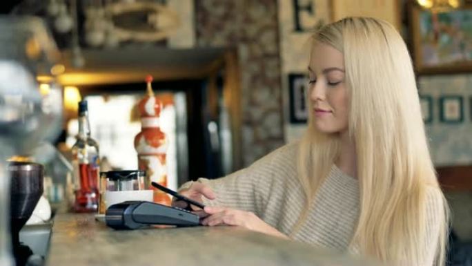 咖啡馆里有吸引力的女性使用智能手机在线支付。4K。