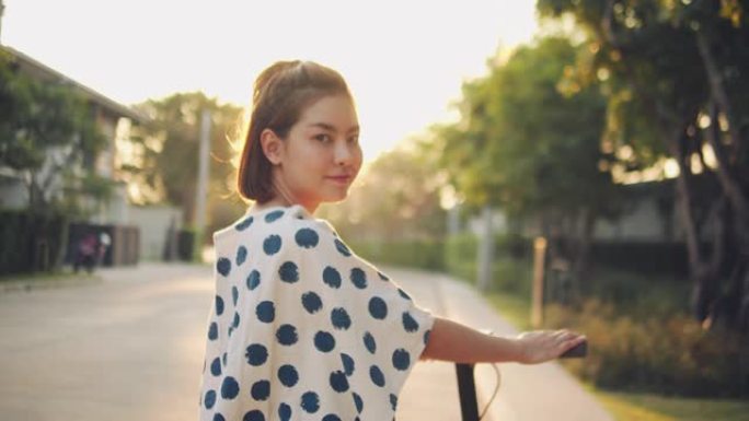 年轻女子在日落时骑着电动踏板车穿越郊区