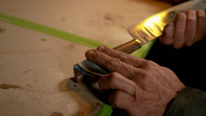 特写: 经验丰富的bladesmith仔细打磨木刀手柄。