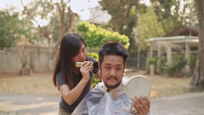 亚洲男子头指向要求在新型冠状病毒肺炎电晕病毒情况下在家用理发推子剃头剪头发，以帮助拉平曲线