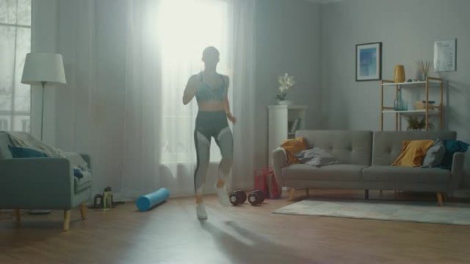 穿着运动服的强壮而美丽的运动健身女孩正在她明亮宽敞的起居室里进行能量慢跑，室内简约。