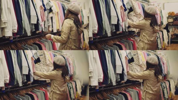 年轻的亚洲妇女在购物中心的架子上选择衣服