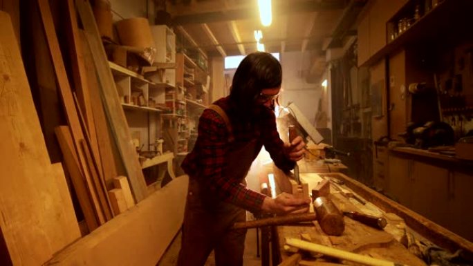 车间男子用锤子和凿子雕刻木条