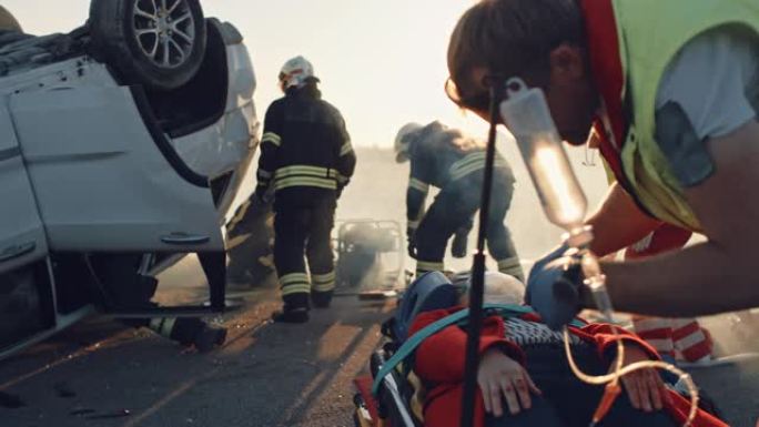 在车祸交通事故现场: 医护人员挽救了躺在担架上的乘客的生命。救援消防员进入翻车以取回其他被困受害者的