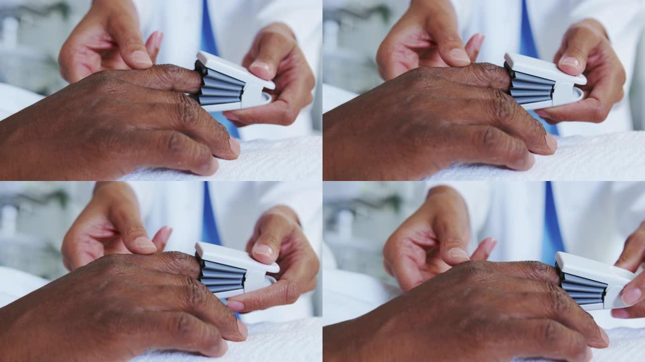 非裔美国女医生在病房的男性患者手上附加脉搏血氧仪的特写