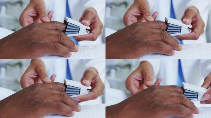 非裔美国女医生在病房的男性患者手上附加脉搏血氧仪的特写
