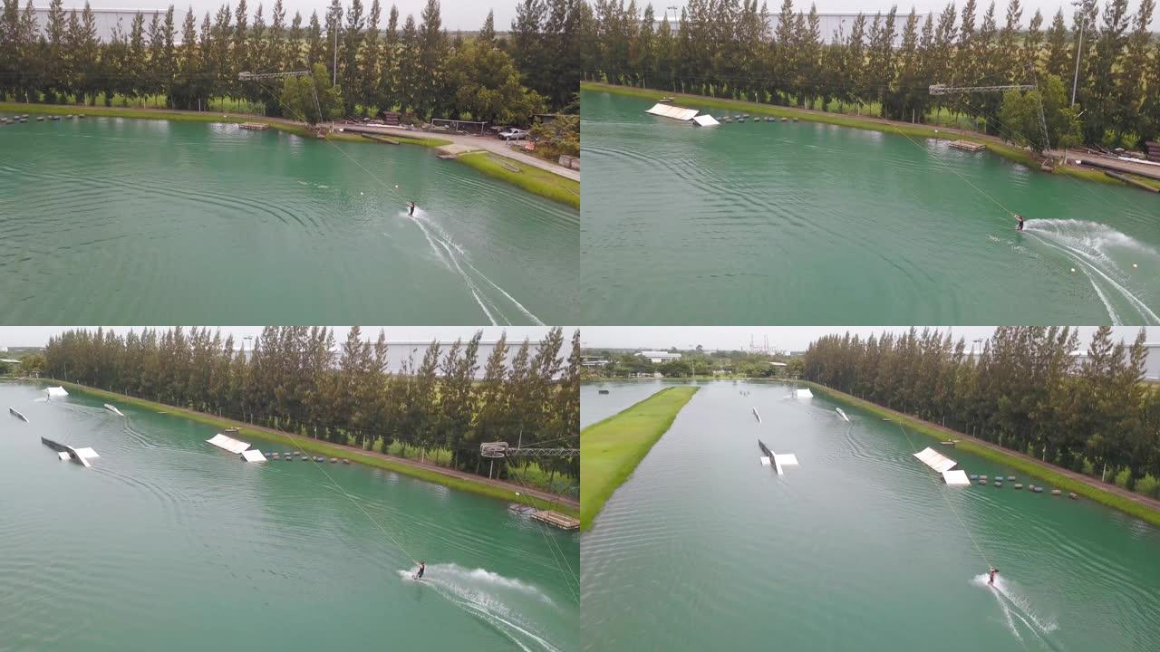空中: 凉爽的滑水者在被钢缆滑水机拖拉时在河上急转弯