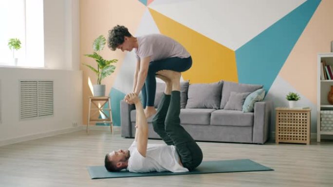 快乐的情侣一起练习双人瑜伽，在公寓里做支撑体式