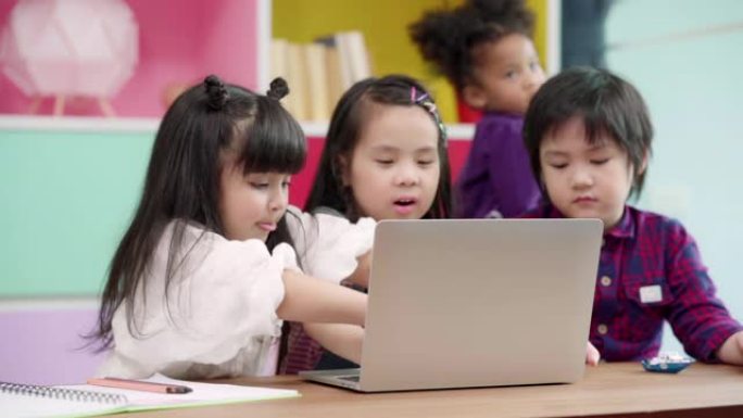 慢动作-一群在教室里使用笔记本电脑的孩子，多种族的年轻男孩和女孩在小学学习时很高兴使用技术。孩子们使
