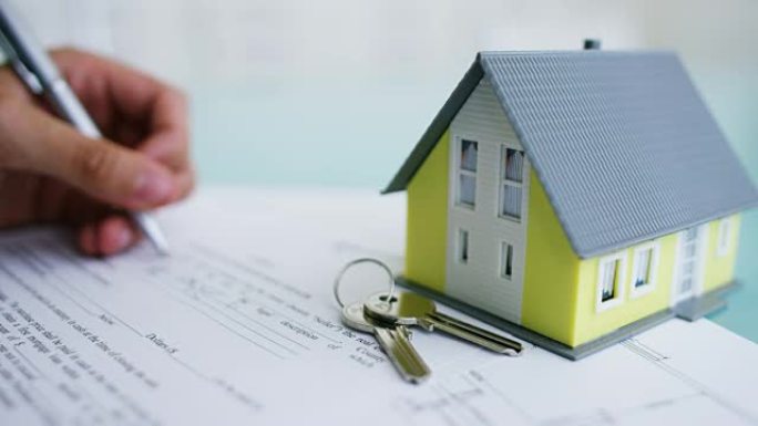 火灾和盗窃保险。保险公司或房地产经纪人的手，显示带有平面图的房屋和带有确保房屋钥匙的文件。