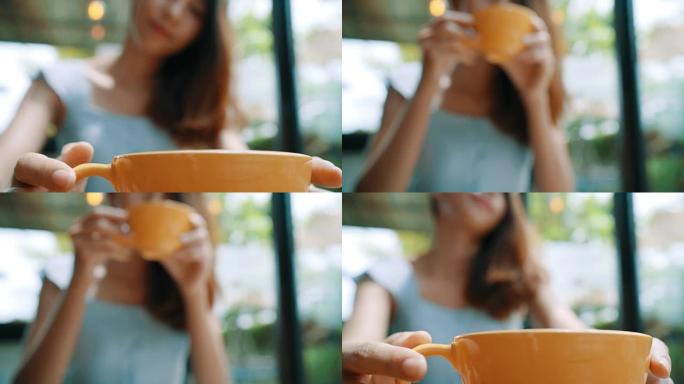 开朗的亚洲年轻女子坐在咖啡馆里喝温暖的咖啡或茶。迷人的快乐亚洲女人捧着一杯咖啡。