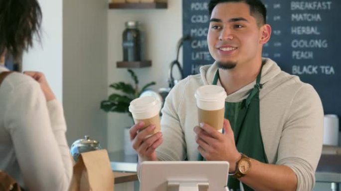 一个年轻的男性咖啡师帮助顾客决定她的饮料大小。