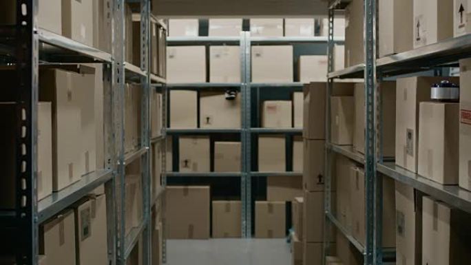 放大仓库储藏室中的移动镜头，成排的货架上摆满了纸板箱、包裹，准备装运。