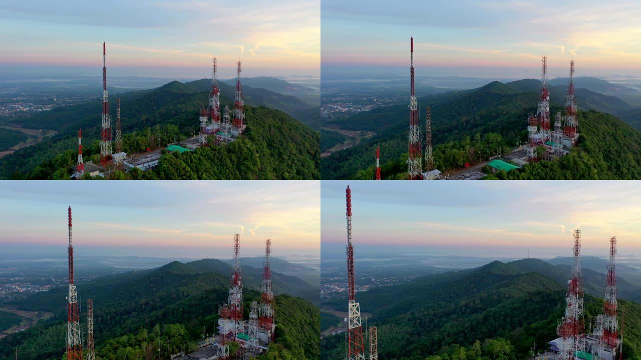 城市上空山上日出时电信桅杆电视天线的鸟瞰图