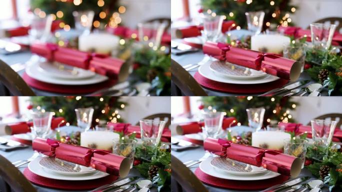圣诞节餐桌的架子焦点照片，盘子和季节性装饰品上排列着红色饼干，背景是一棵圣诞树，有灯光，选择性焦点