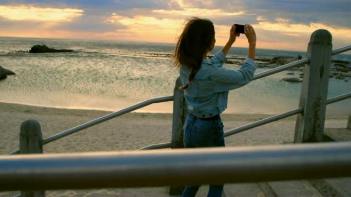 女人在4k海滩用手机点击照片