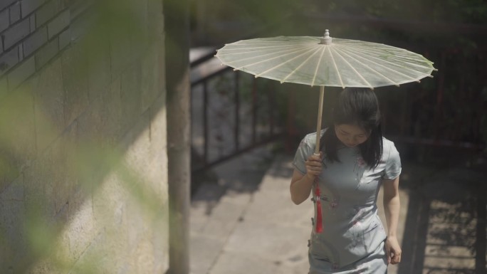 江南雨巷穿着旗袍的美女撑着油纸伞走上石梯