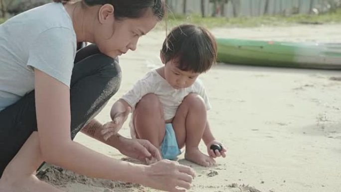 亚洲母亲和她的儿子在沙滩上玩沙子