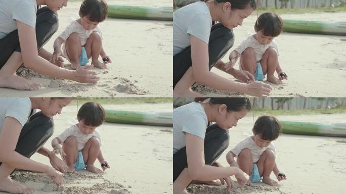 亚洲母亲和她的儿子在沙滩上玩沙子