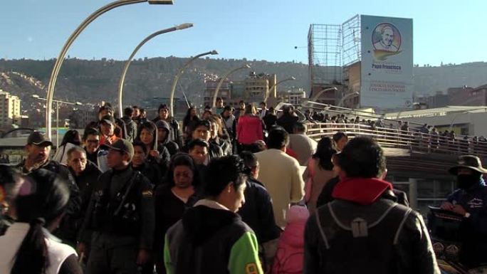 在玻利维亚拉巴斯拥挤的桥上运动。背景中的教皇方济各海报。