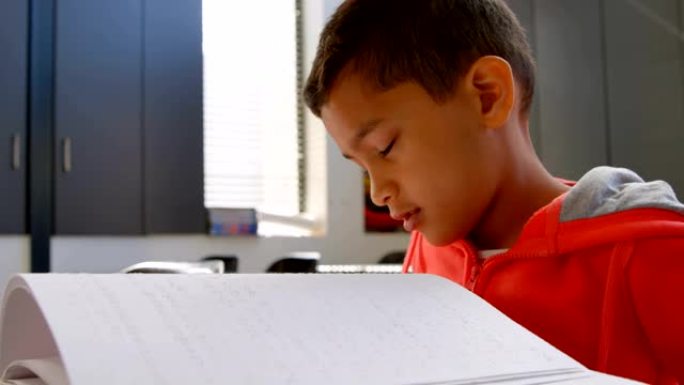 4k学校教室里盲人亚洲男生手读盲文书的侧视图