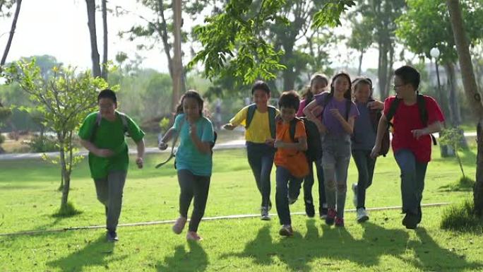 在阳光明媚的夏日，男孩和女孩在放学后穿着便装在公园里跑步。