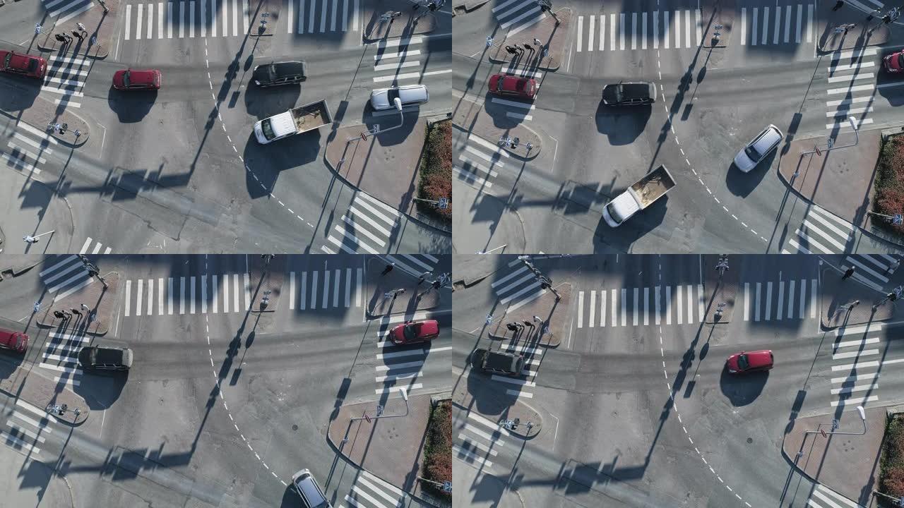 在阳光明媚的日子里，城市十字路口人行横道的空中无人机镜头。汽车在道路上双向行驶。