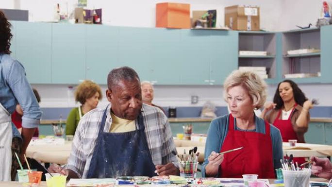 一群退休的老年人与老师一起在社区中心参加艺术课