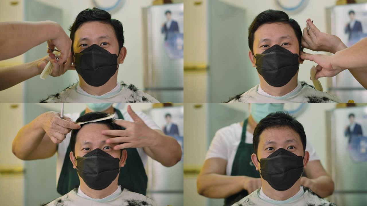 一个年轻有魅力的男人戴着防护医疗面罩，在家里剪头发的时候看着相机。居家隔离疫情防控。