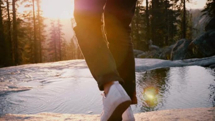 在约塞米蒂公园慢动作的岩石上，女性的腿小心翼翼地踩着美丽的小溪。