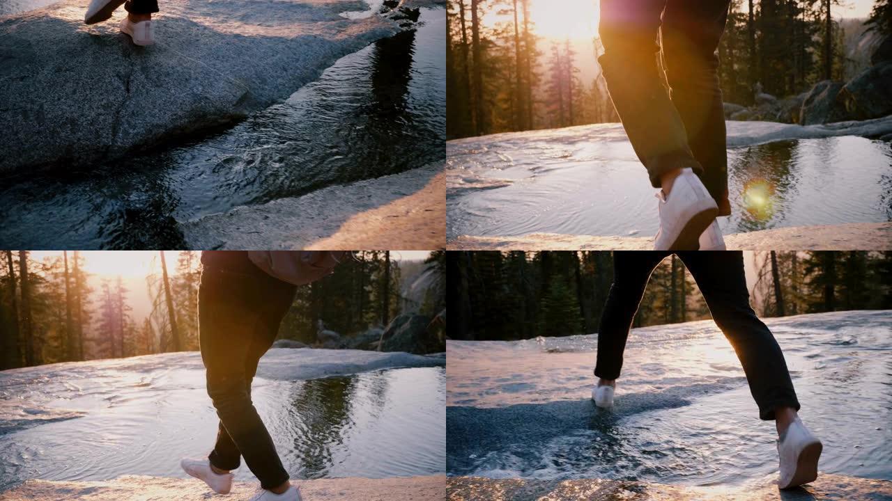 在约塞米蒂公园慢动作的岩石上，女性的腿小心翼翼地踩着美丽的小溪。