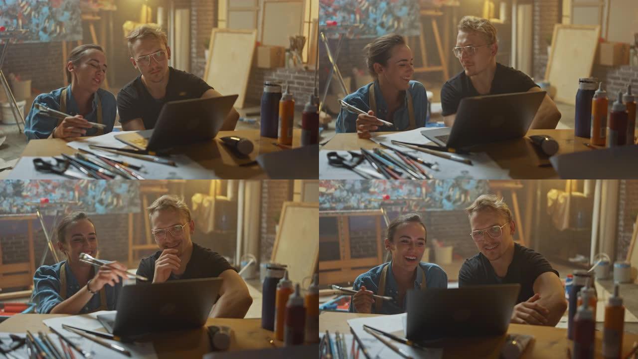 坐在工作室里的几位艺术家使用笔记本电脑，从事一个项目，交谈和微笑。画家和她的搭档做研究。带油画和工具