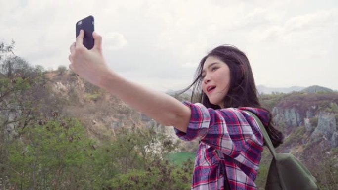 博主亚洲背包客女人在山顶上录制vlog视频，年轻女性使用手机快乐让vlog视频享受徒步冒险的假期。生