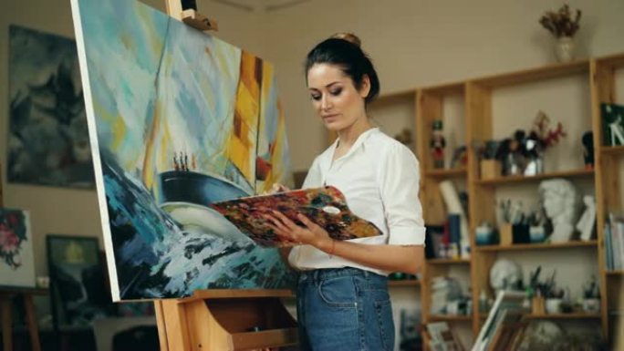 熟练的女画家独自在工作室工作，用油画、调色板和画笔在画架上画画，享受她的职业。人和工作理念。
