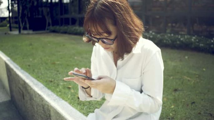 女人在日落时在花园里工作，并使用智能手机