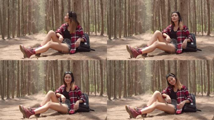 亚洲徒步旅行者女人在森林里徒步旅行。年轻快乐的背包女孩坐着休息累了散步后旅行自然冒险之旅，在暑假爬山