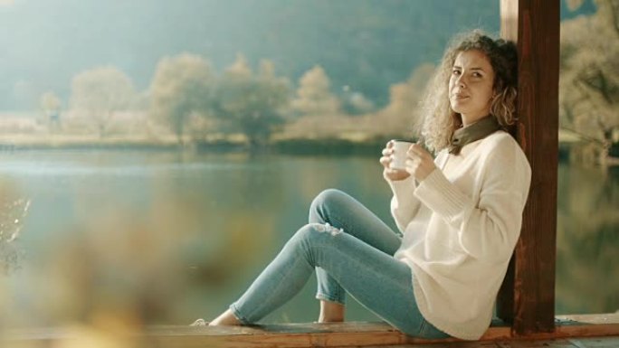 女人坐在湖边喝咖啡